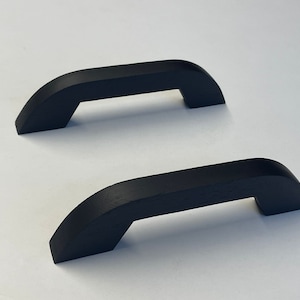 Pode incluir: Duas puxadores de armário de madeira preta com um design curvo.