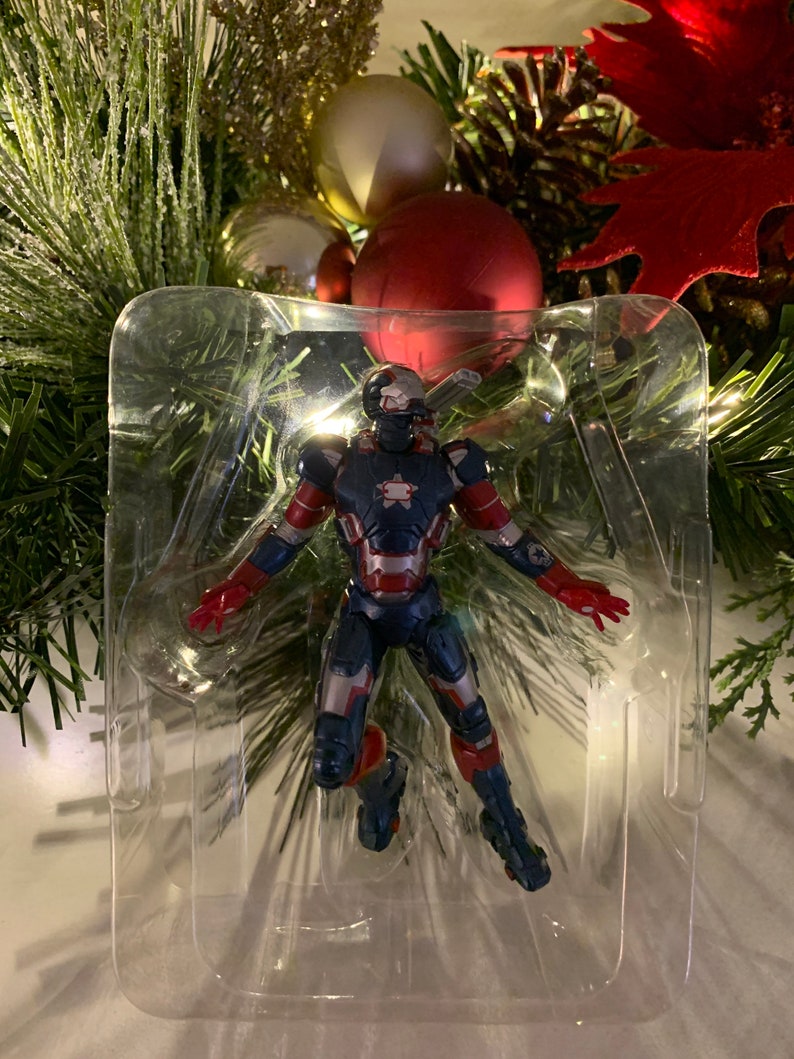 May include: A red, white and blue action figure of Iron Man in a clear plastic display case. The figure is in a flying pose with arms outstretched.