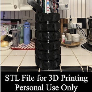 May include: A cylindrical storage container constructed from six stacked black hockey pucks with a textured grip surface. The container holds several hockey sticks and features the text STL File for 3D Printing Personal Use Only.
