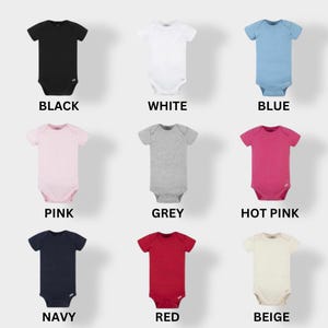 May include: Nine baby onesies in different colors: black, white, blue, pink, grey, hot pink, navy, red, and beige. The onesies are all short-sleeved and have a snap closure at the bottom.