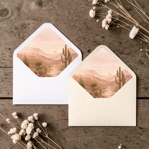 Pu&ograve; includere: Due buste aperte con all'interno un'illustrazione di un paesaggio desertico. Una busta &egrave; bianca, l'altra color crema. La scena del deserto presenta cactus, montagne e un sole al tramonto nei toni del marrone e pesca. Fiori secchi sparsi.