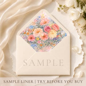 以下が含まれることがあります： ピンク、ピーチ、ブルーの色合いの水彩画のバラと野の花が特徴の、フローラルライナー付きの開いたクリーム色の封筒。「SAMPLE」の文字が封筒に印刷されています。「SAMPLE LINER | TRY BEFORE YOU BUY」の文字が下にあります。