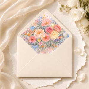 Puede incluir: Un sobre crema abierto con un dise&ntilde;o floral en el interior. El dise&ntilde;o floral presenta una variedad de flores en tonos rosa, melocot&oacute;n, amarillo y azul. El sobre est&aacute; sobre una superficie blanca texturizada.