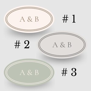 以下が含まれることがあります： 「A & B」の文字が入った3つの楕円形のステッカー。ステッカーはベージュ、グレー、グリーンの色合いで、それぞれ二重の縁取りがされています。各ステッカーの横には数字の1、2、3が印刷されています。