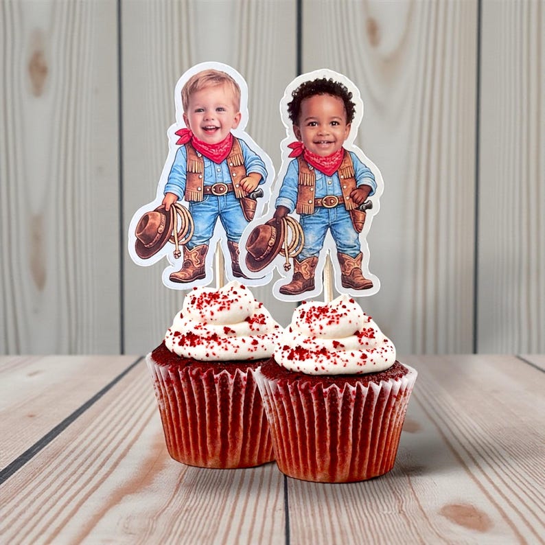 May include: Two cupcakes with white frosting and red sprinkles, topped with cowboy-themed toppers. The toppers feature illustrations of children dressed as cowboys, complete with hats, boots, and bandanas. The cupcakes sit on a wooden surface.