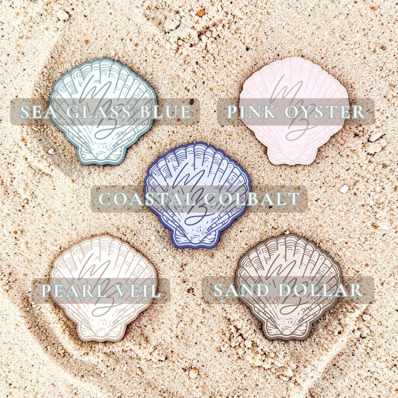Op de afbeelding: Vijf schelpvormige stickers in verschillende kleuren, waaronder blauw, roze en beige. De stickers zijn gelabeld met "Sea Glass Blue", "Pink Oyster", "Coastal Cobalt", "Pearl Veil" en "Sand Dollar". Elke sticker heeft een schelpontwerp en de letters "M Z".