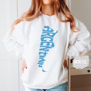 May include: White sweatshirt with a blue outline of the country of Argentina, with the word "Argentina" spelled out within the outline.