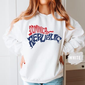 May include: White sweatshirt with a blue and red graphic of the Dominican Republic. The graphic is shaped like the island and the words "Dominican Republic" are spelled out within the outline of the island.