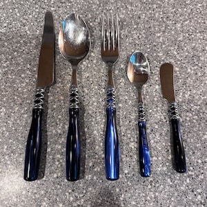 May include: Set of five silver-toned cutlery pieces with blue marbled handles. The set includes a knife, fork, two spoons, and a butter knife.