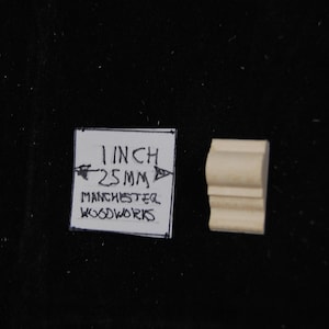 May include: A close-up of a small, unfinished wooden molding piece. The molding is 1 inch (25 mm) wide and is labeled "Manchester Woodworks".