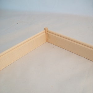 Puede incluir: Una esquina de moldura de madera, mostrando los bordes biselados de las dos piezas.