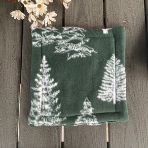 May include: A green fleece pot holder with a white pine tree design. The pot holder has a white stitched border.