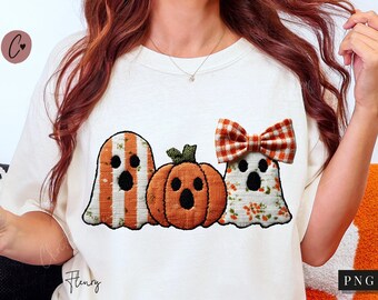 Könnte beinhalten: Cremefarbenes T-Shirt mit einem Halloween-Motiv. Das Design umfasst zwei Geisterfiguren und einen Kürbis, alle mit schwarzen Gesichtern. Der Geist rechts hat eine karierte Schleife. Auf dem Shirt steht das Wort "Flenry".