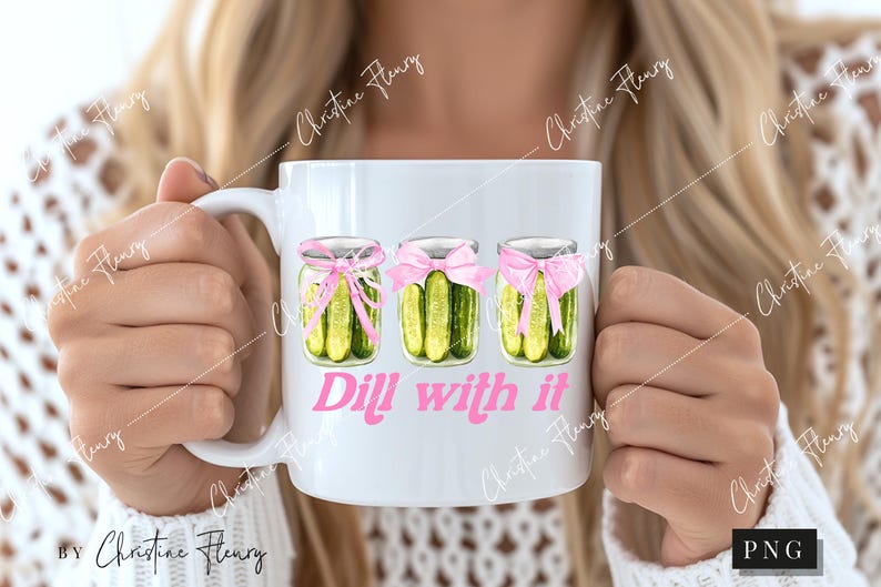 May include: White ceramic mug with a pink and green design of three jars of dill pickles with pink bows. The text "Dill with it" is printed in pink below the jars.