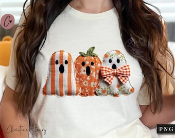 Könnte beinhalten: Ein weißes T-Shirt mit drei Halloween-Applikationen. Die Applikationen zeigen zwei Geister und einen Kürbis, alle in Orange, Weiß und Grün. Ein Geist hat orangefarbene Streifen, der andere eine Fliege. Der Kürbis ist in der Mitte.