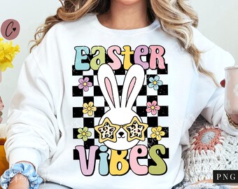 May include: White sweatshirt featuring a checkered background, a cartoon bunny wearing sunglasses, and the text "Easter Vibes" in colourful letters.