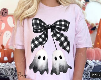Puede incluir: Camiseta rosa claro con un lazo a cuadros blanco y negro y dos ilustraciones de fantasmas. Los fantasmas tienen ojos negros y un diseño sombreado y fluido. La camiseta forma parte de un tema de Halloween.