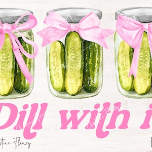 May include: Three glass jars filled with dill pickles tied with pink ribbon bows. The jars are on a white wood background with the text "Dill with it" in pink letters.