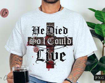 Puede incluir: Camiseta gris claro con un diseño de cruz. La cruz es de madera y alambre de púas, con las palabras "He Died So I Could Live" en letras góticas. Salpicaduras de pintura roja acentúan el diseño.