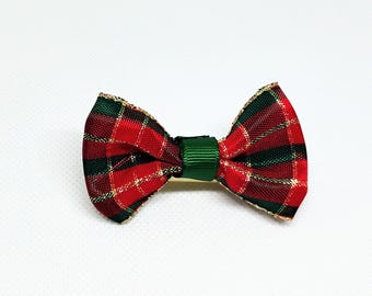 May include: A red and green plaid bow tie with gold glitter accents. The bow tie is made of fabric and has a green center.