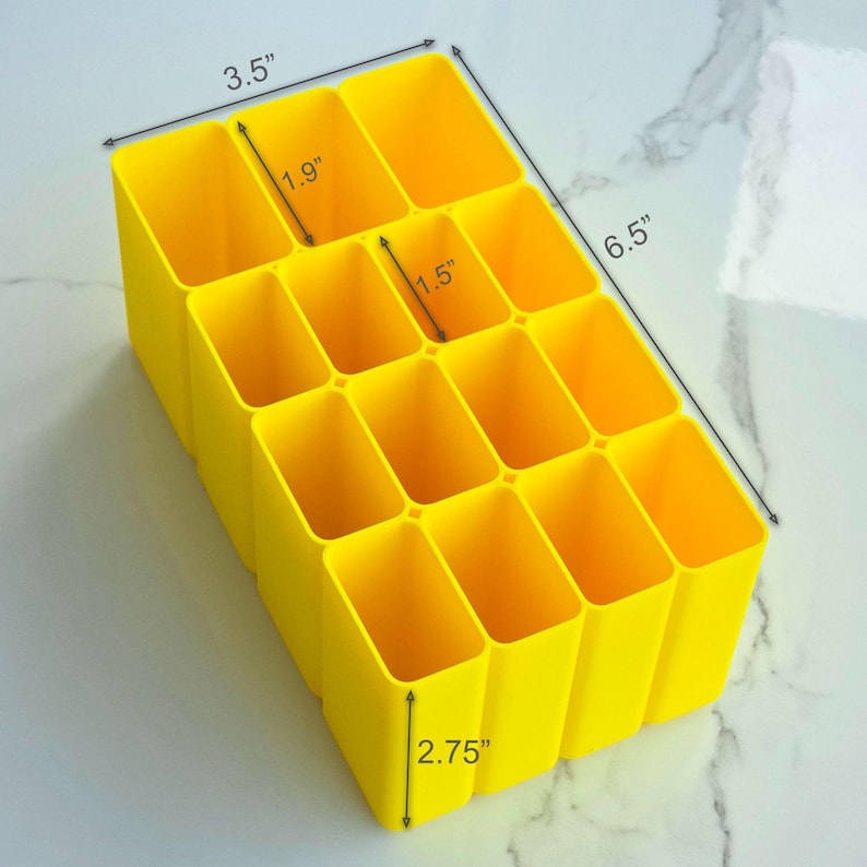 May include: A bright yellow organiser with 12 rectangular compartments. The organiser is 16.5 cm long, 8.9 cm wide, and 7 cm tall. Each compartment is 4.8 cm wide and 3.8 cm deep. Suitable for desk organisation.