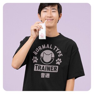 May include: A black t-shirt with a pink graphic of a cat in a circle with the text "Normal Type Trainer" and the Japanese word for "Normal" in pink text.