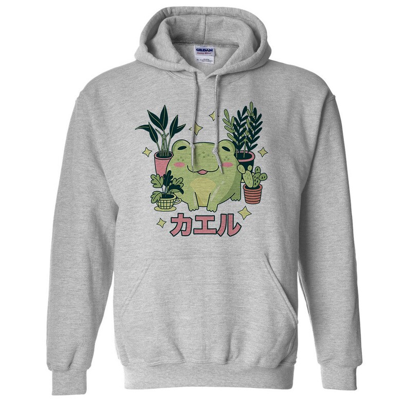 May include: A gray hoodie with a green frog sitting among potted plants. The frog is smiling and the text "カエル" is printed below the frog.