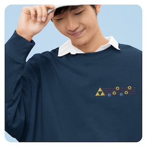 May include: A navy blue sweatshirt with a gold triangle and musical notes embroidered on the front. The notes are in red, yellow, and blue.