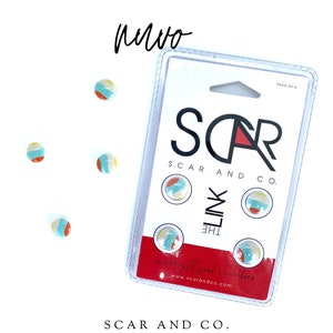 Op de afbeelding: Een pak met vier kleurrijke ronde stickers met een strandbalontwerp. De stickers bevinden zich op een witte kaart met de tekst "SCAR AND CO. THE LINK" en "were got your number www.scarandco.com".