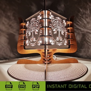 Puede incluir: Una lámpara de madera con un diseño de nudo celta. La lámpara está encendida y proyecta un cálido resplandor. La lámpara está cortada con láser y lista para ensamblar. La imagen incluye el texto "LASER READY CUT FILE" y "INSTANT DIGITAL DOWNLOAD".