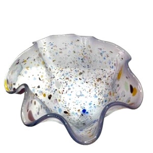 Peut inclure: Un bol en verre transparent avec un bord festonné et un motif moucheté de blanc, bleu, jaune et marron. Le bol est en verre et a une teinte légèrement violette.