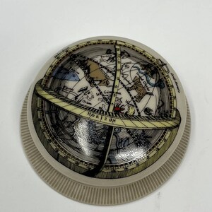 May include: A white ceramic globe with a detailed illustration of constellations and celestial bodies. The globe is surrounded by a ring with the word "HORIZON" printed on it. The globe is labeled with French text, including "Meridien" and "Grand Ourse".