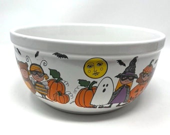 May include: White ceramic bowl with a Halloween theme. The bowl features a cartoon illustration of children dressed in costumes, pumpkins, bats, and a ghost.