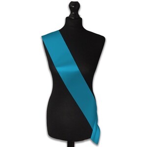 May include: A turquoise blue satin sash, draped diagonally across a black mannequin.