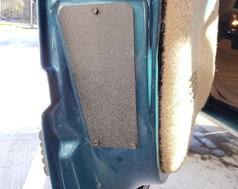 May include: A close-up of a teal car door with a black sound deadening panel. The panel is rectangular and has a textured surface. The door is open and the interior is visible.