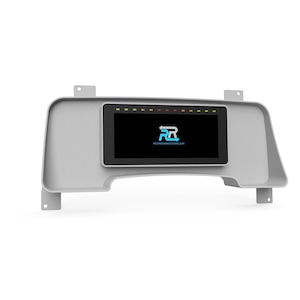 May include: A gray dashboard panel with a rectangular black screen displaying a logo and website address. Above the screen are several small colored lights. The panel has a molded design with mounting tabs.