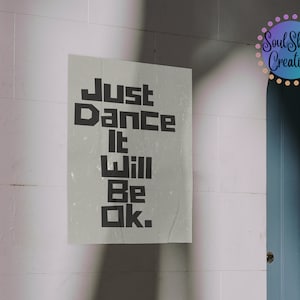 May include: A white poster with black text that reads "Just Dance It Will Be Ok." The poster is hanging on a white brick wall.
