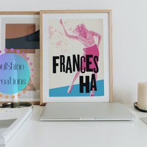 May include: A framed poster with a vintage design featuring a woman dancing. The poster is in pink, blue, and white with the text "FRANCES HA" in black.
