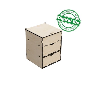 Puede incluir: Una caja de almacenamiento de madera con tres cajones y una tapa con bisagras. La caja está hecha de madera clara y tiene un acabado natural. Los cajones son todos del mismo tamaño y tienen un borde negro. La caja está sobre un fondo blanco. "Probado en mi máquina láser" está escrito en una pegatina circular verde.