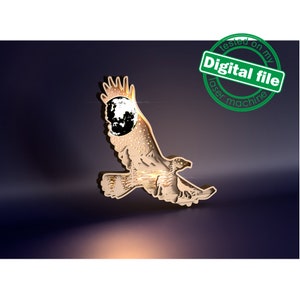 Puede incluir: Un águila de madera con una luna recortada en su ala, iluminada desde atrás. El águila está volando con las alas extendidas. La imagen tiene un fondo azul oscuro y un brillo claro alrededor del águila.