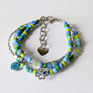 Puede incluir: Pulsera de cuentas de varias hebras con cuentas azules, verdes y transparentes. La pulsera incluye un dije de corazón plateado, un dije de trébol de cuatro hojas y un dije de piedra azul. Mide aproximadamente 18 cm de largo.