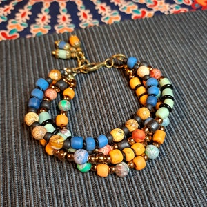 Peut inclure: Bracelet multi-rangs avec des perles bleues, orange, vertes et brunes. Le bracelet a un fermoir en métal et est fait de différents matériaux.