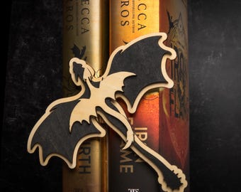 May include: A wooden dragon bookend with black wings, holding two books titled "Fire & Flame" and "Earth" by Rebecca Yarros.