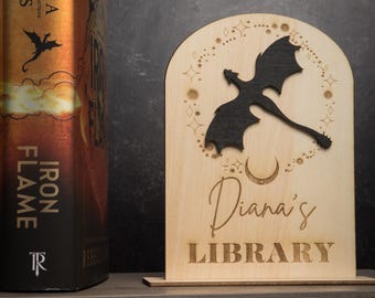 May include: A wooden bookend with a black dragon silhouette, stars, and a crescent moon. The bookend is personalized with the text "Diana's Library".