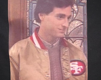 Bob Saget “Danny Tanner” Gold 49er Jacket Premium T-Shirt in Mens sizes S-3XL in white or black! Heat Pressed on Kirkland brand T-Shirts!
