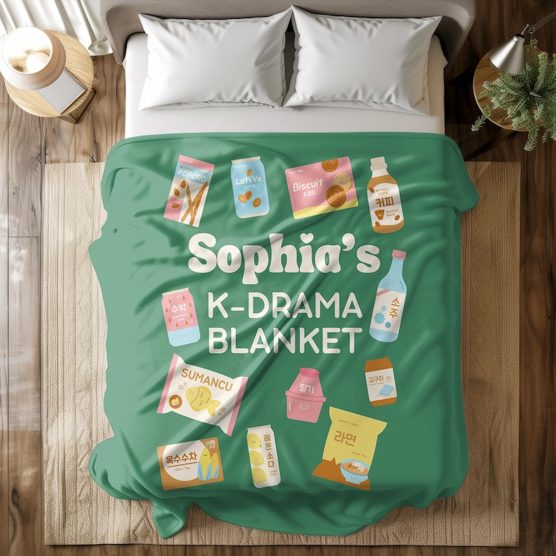 May include: A green blanket with the text "Sophia's K-DRAMA BLANKET" and various food and drink illustrations. The blanket features images of snacks, drinks, and a bottle of soju, perfect for a cozy night in.