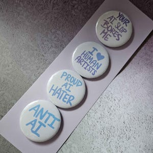May include: Four white round buttons with blue text. The buttons read "ANTI AI", "PROUD AI HATER", "I LOVE HUMAN ARTISTS", and "YOUR AI SLOP BORES ME". The buttons are arranged on a light purple background.