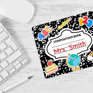 May include: Black and white composition book with a black and white checkered pattern. The book has a white label with the text "COMPOSITION BOOK" and "Mrs. Smith" in red text. The book has various colorful stickers including a rainbow, a globe, a stack of books, and letters.