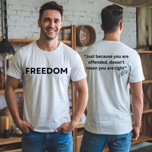 May include: White t-shirt with the word "FREEDOM" printed in black on the front. The back of the shirt features the quote, "Just because you are offended, doesn't mean you are right."