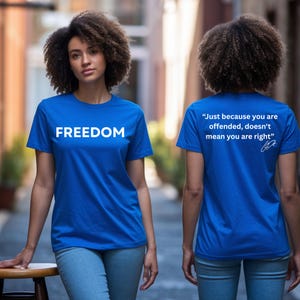 May include: A royal blue t-shirt with the word "FREEDOM" in white block letters. The back of the shirt has the quote, "Just because you are offended, doesn't mean you are right" in white, with a signature.